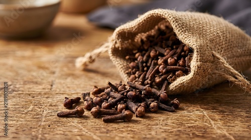 Fragrant Dried Cloves Spilling from a Rustic Burlap Sack on Wood