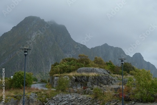 Rocky coastline with waves crashing against stones, distant islands visible under a cloudy sky in Lofoten Islands, Norway during the month of September