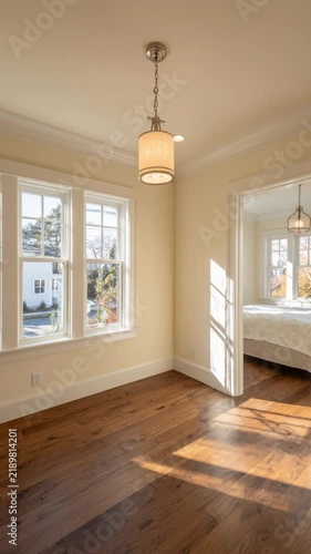 Bright and spacious living room with beautiful wooden floors, large windows allowing natural light and a modern chandelier creating an inviting atmosphere for relaxation.