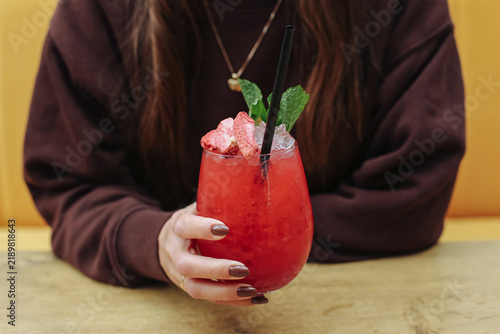 Sticker Woman holding red cocktail with ice background