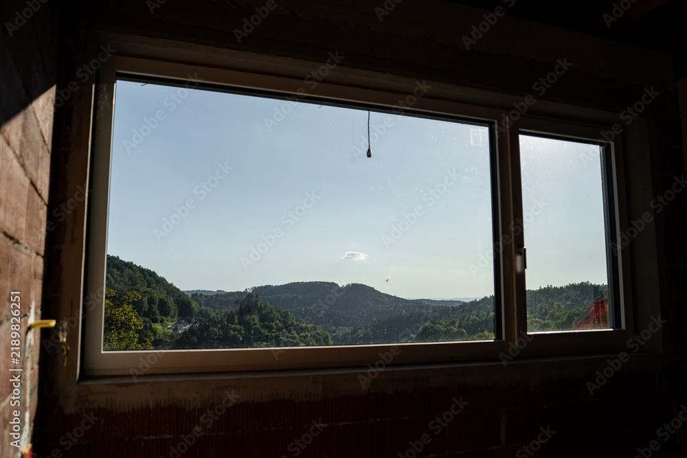 Fototapeta premium Modern window frame with a view of trees in a house under construction