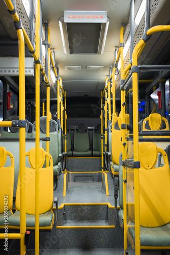 Vertical photograph of the illuminated interior of a modern urban bus without passengers.