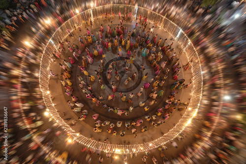 Aerial shot of a large Garba circle dance with decorative lights and motion blur.
