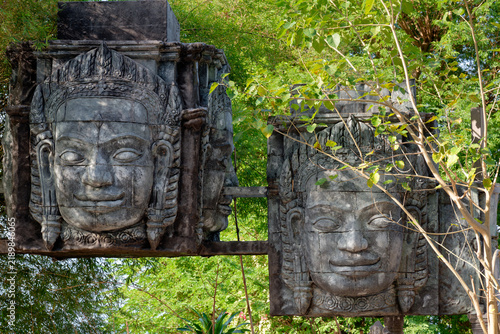 Khmer style stone face sculptures among green foliage in Thailand