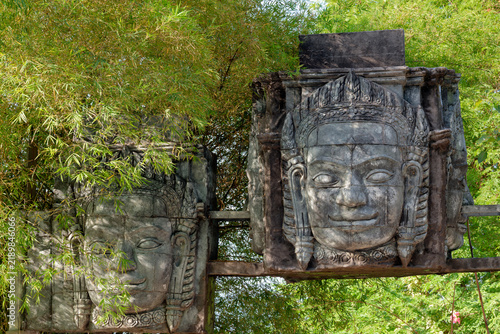 Khmer style stone face sculptures among green foliage in Thailand