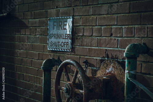 Фотография Rusty fire sprinkler shut off valve and warning sign on brick wall