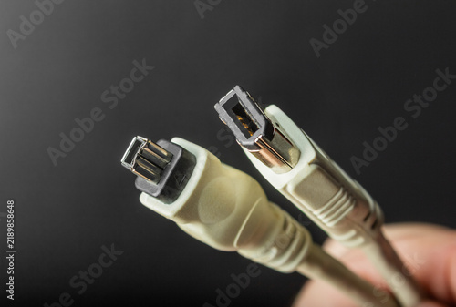 Photo of a hand holding firewire sound board input cables on black background.