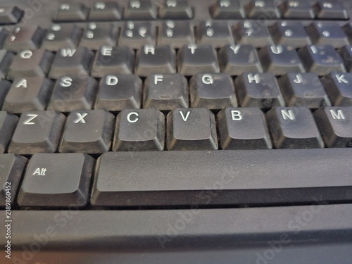 Fotografie Close-up of a dusty black computer keyboard with worn keys and visible particles