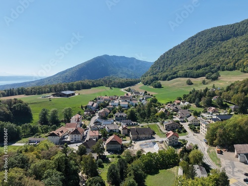 Naklejka Sunlit village nestled among rolling green hills