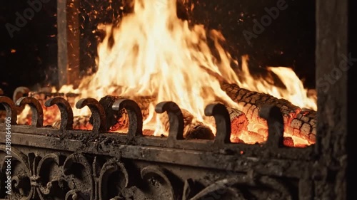 Warm burning firewood inside a dark vintage iron fireplace with glowing embers and bright dancing flames
