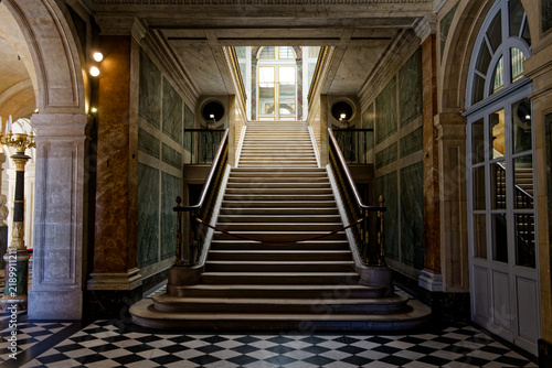 Fotografie Empty grand marble staircase with a checkered floor and rope barrier inside the historic Palace of Versailles, France
