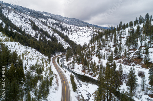 Winter road snakes through snow-dusted pine forests
