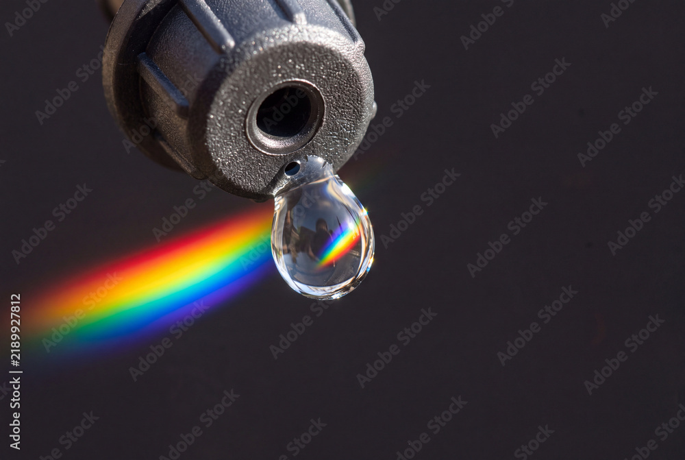 Obraz premium Refracted emitter droplet rainbow prism at irrigation point macro
