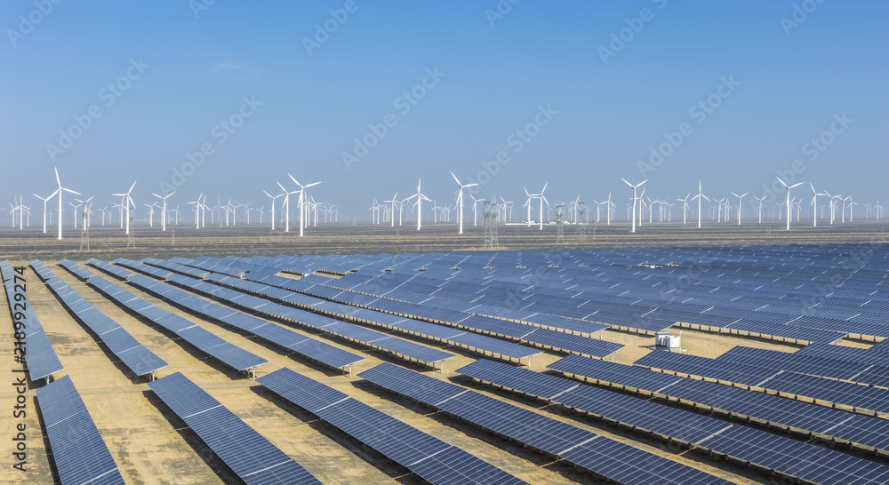 Obraz premium Solar Photovoltaic Farm and Wind Turbines in Desert Landscape