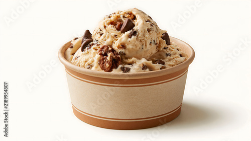 Scoop of caramel ice cream with pecan pieces and chocolate chunks, served in a paper cup, on a white background