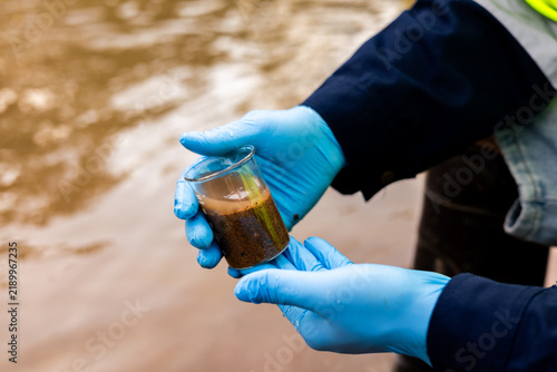 Fotografie Environmental technician collecting river sediment sample for contaminant and heavy metal analysis