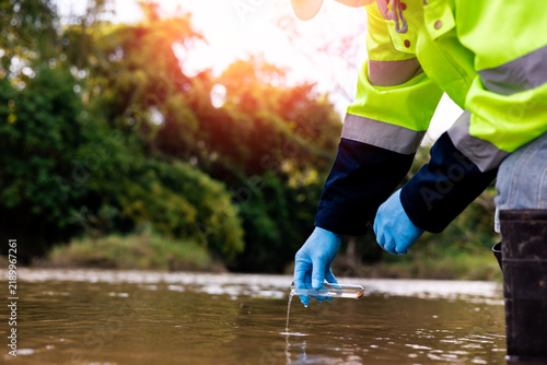 Field worker collecting source water sample to assess quality and safety for drinking water treatment.