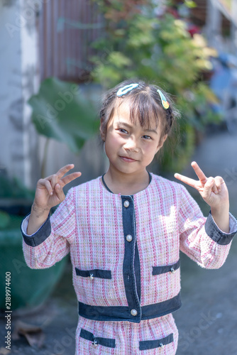 Happy little boy showing thumbs up sign outdoors in a green park, smiling cheerfully and expressing joy, fun, happiness, and positive childhood lifestyle in nature