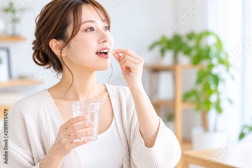 Obraz na płótnie 水を飲みながらサプリメントを摂取する日本人の女性