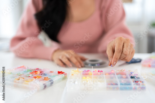 female hobby Handmade jewelry making. Close up hands of Young woman creating bracelets at home workshop.