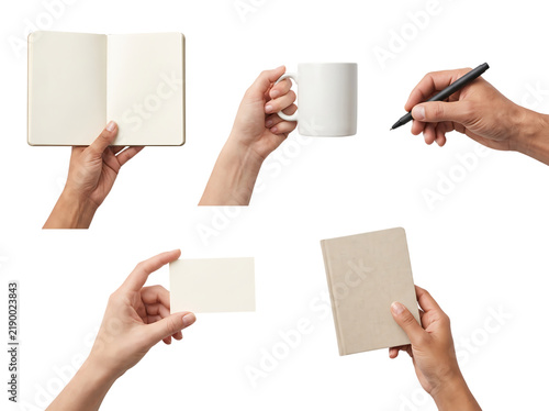 Hands holding various blank items including open notebook white coffee mug ballpoint pen business card and craft paper book for branding and identity.
