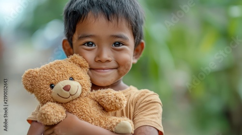 A portrait of an orphan kid holding a teddy bear, looking hopeful and happy.