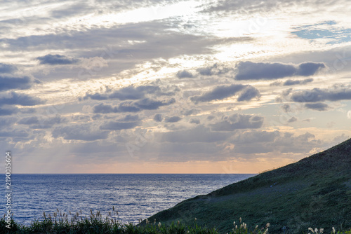 Tapety artystyczne 雲間から海へ光が降り注ぐ夕暮れの海岸風景