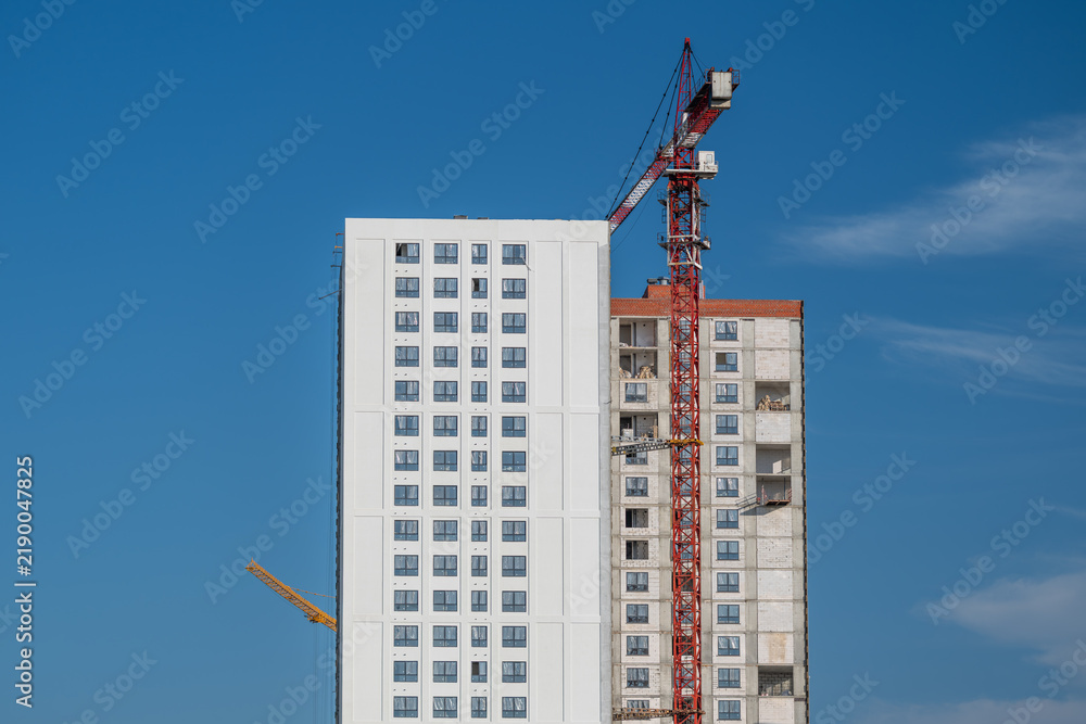 Fototapeta premium Sky-high construction contrasts modern design and raw structure against a brilliant blue sky in a bustling urban landscape