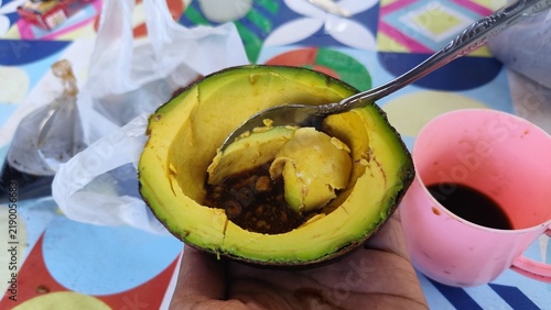 фотографія Fresh ripe avocado served in its natural half shell with sweet dark syrup, enjoy