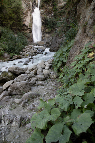 Obraz na plátne Waterfall cascading down rocky mountainside with river