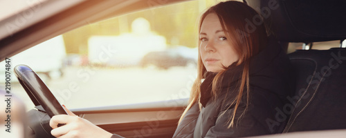 Bild auf Leinwand An adult woman sits behind the wheel of a car, focused on the road ahead