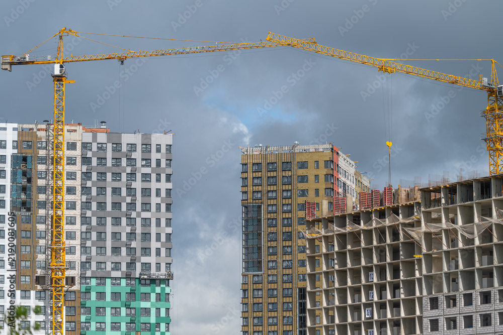 Fototapeta premium Construction progress in a bustling city skyline showcases cranes and new buildings under dramatic clouds