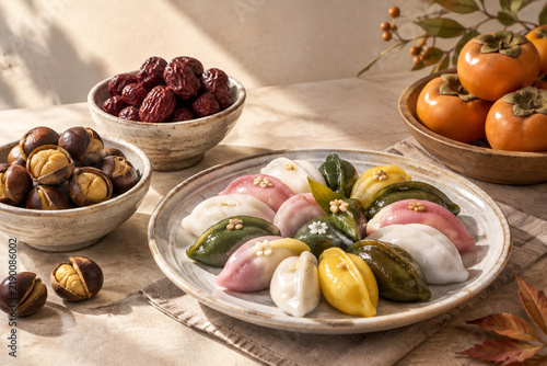 Ceramic plate of songpyeon with chestnuts, jujubes, persimmons, harvest season still life