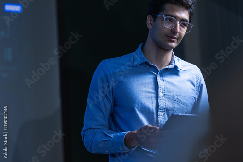 Foto A young male analyst with dark curly hair and clear framed glasses in a light bl