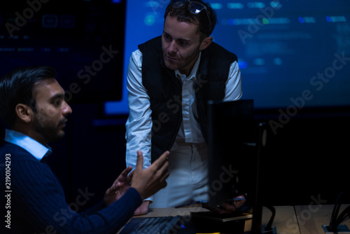 Fotografie A bespectacled male team lead in a dark gilet and rolled white sleeves shares ex