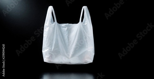 Single white plastic shopping bag floats empty against dark backdrop. Recyclable carrier bag, studio shot, clean minimal design. Retail product, disposable item.