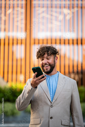Bild auf Leinwand Happy man communicating on smartphone using speakerphone