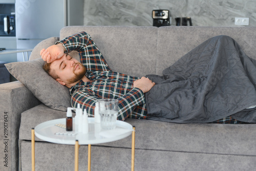 Foto Man resting on couch feeling unwell with fever