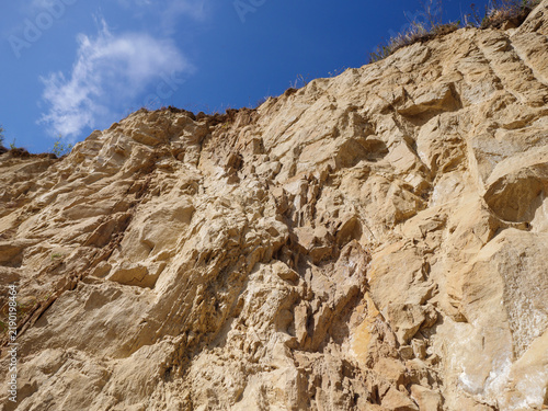 Canvastavla Steep exposed sandstone slope with weathered rock layers, erosion and sparse vegetation beneath a deep blue sky, showing natural geological structure and dry terrain