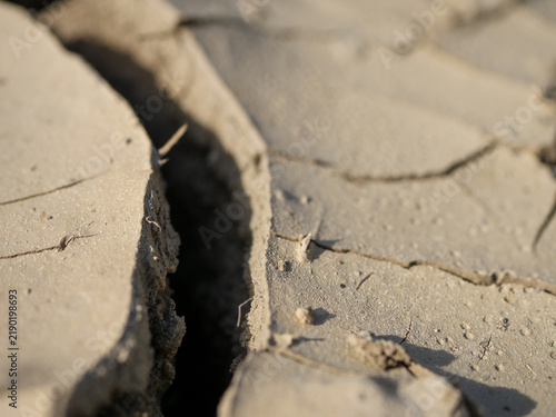 Fotografie Deep fissure in severely cracked dry soil during extreme drought, showing parched earth, loss of moisture and land degradation caused by prolonged water scarcity