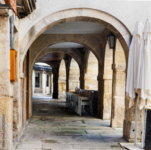 Bild auf Leinwand Stone Archway and Stacked Chairs in Historic City, Lugo, Spain