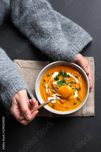 Woman in knitted sweater eating fresh pumpkin soup