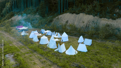Fotografie Historical reenactment camp with many white tents set up on a grassy clearing fo