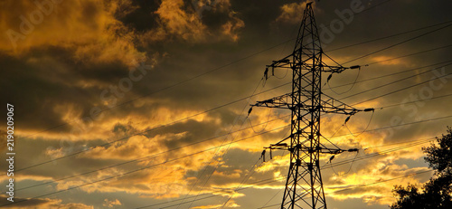 Electricity pylon silhouette against a golden sunset sky