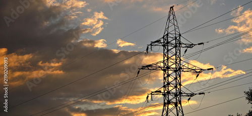 Electricity pylon silhouette against layered sunset clouds