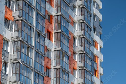 Quadro su tela Modern building facade reflects sunlight as it rises against a clear blue sky, s