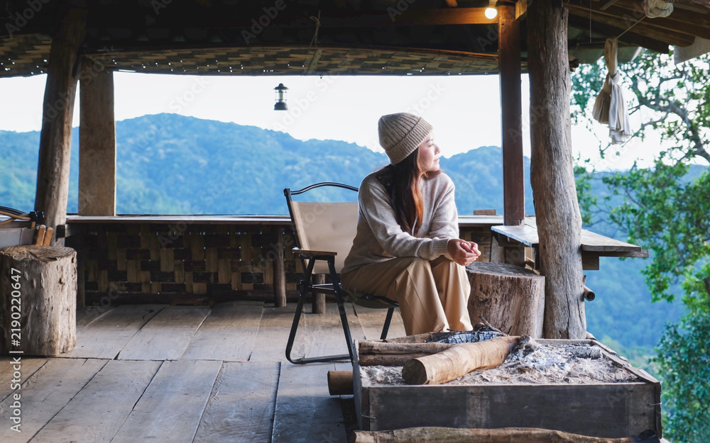 Fototapeta premium A woman sitting on wooden terrace and looking at nature views