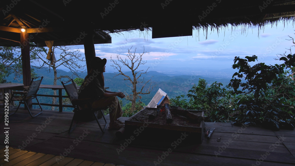 Fototapeta premium A woman sitting on wooden terrace and looking at nature views