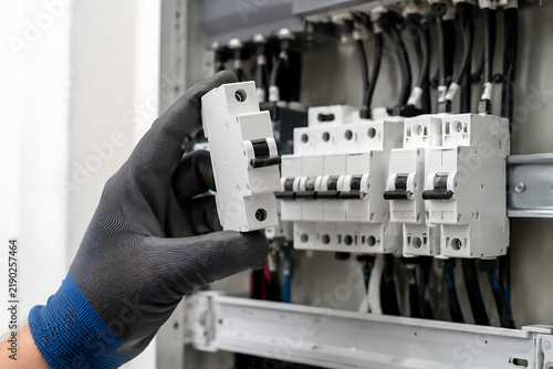 Electrician installing a circuit breaker inside a metal electrical panel with wiring