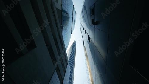 Dynamic upward perspective of modern glass office skyscrapers reflecting daylight.